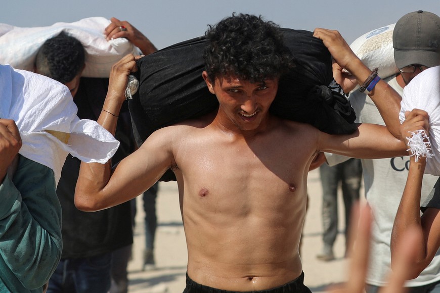 Palestinians carry aid supplies that entered Gaza through Israel, in Beit Lahia, northern Gaza Strip, August 2, 2025. REUTERS/Mahmoud Issa