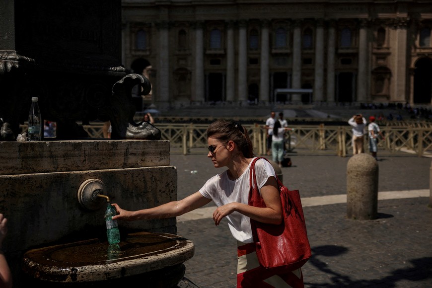 FILE PHOTO: A visitor fills her bottle with water from a fountain on St. Peter’s Square, during a heatwave, at the Vatican, July 23, 2025. REUTERS/Alkis Konstantinidis/File Photo