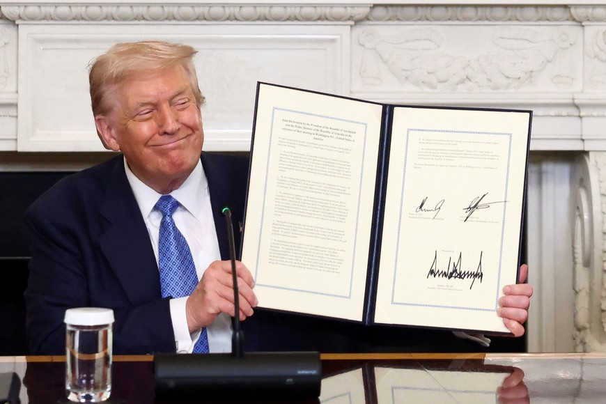 U.S. President Donald Trump smiles as he holds a document during a trilateral signing event with Armenia's Prime Minister Nikol Pashinyan and Azerbaijan's President Ilham Aliyev (not pictured), at the White House, in Washington, D.C., August 8, 2025. REUTERS/Kevin Lamarque