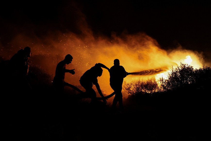 Locals try to extinguish a wildfire burning in Keratea, near Athens, Greece, August 8, 2025. REUTERS/Stelios Misinas     TPX IMAGES OF THE DAY