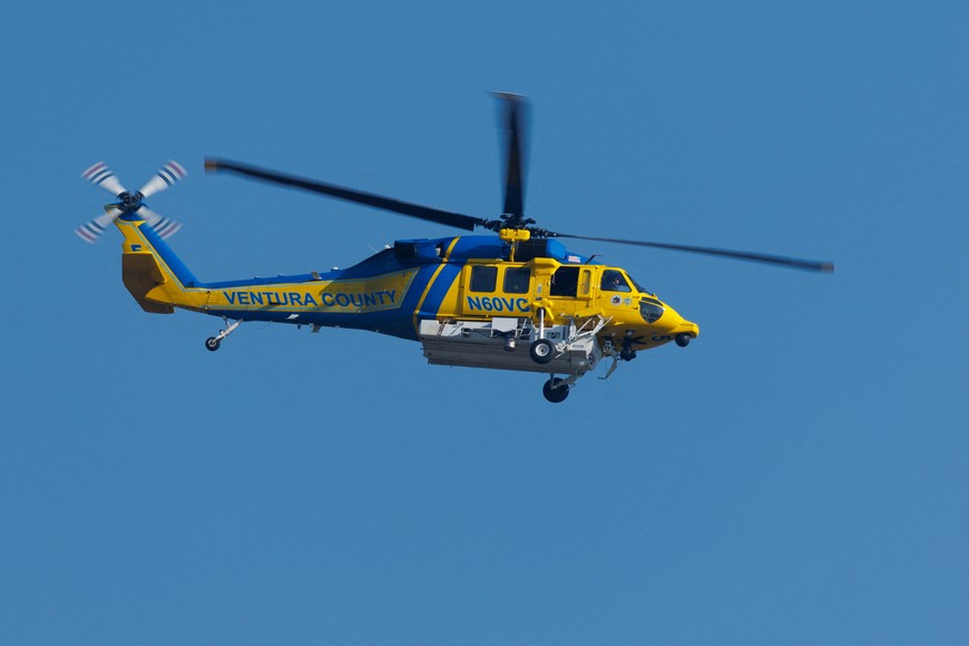 A Ventura County firefighting helicopter heads back to pick up more water after making a drop on the Canyon wildfire in the hills north-east of Los Angeles in Ventura County, California, U.S., August 8, 2025. REUTERS/Mike Blake