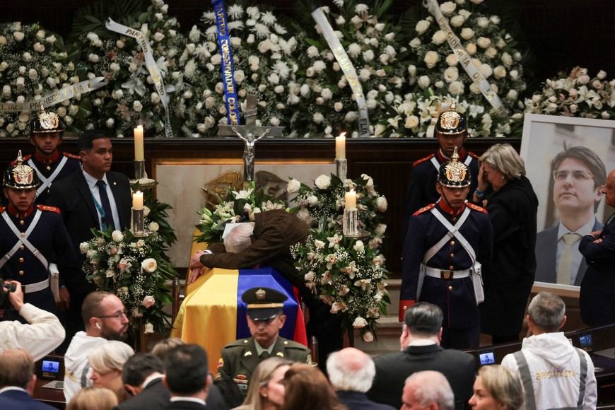 Miguel Uribe Londono, father of Colombian Senator Miguel Uribe Turbay, who died two months after he was shot in the head at a campaign event, leans over the coffin of his son during a tribute at the Colombian congress, in Bogota, Colombia August 12, 2025. REUTERS/Luisa Gonzalez