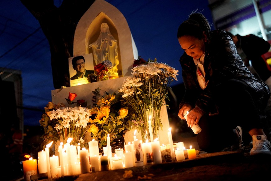 A woman lights a candle at a memorial set up at the site where Colombian Senator Miguel Uribe Turbay was shot in the head on June 7 during a campaign event, after his death, in Bogota, Colombia August 11, 2025. REUTERS/Sergio Acero Yate REFILE - CORRECTING FROM "PEOPLE LIGHT CANDLES" TO "A WOMAN LIGHTS A CANDLE".