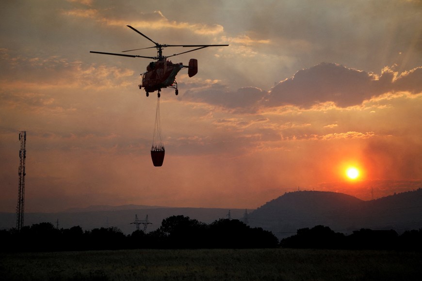 A firefighting helicopter flies over Rogami suburb during sunset, as temperature rises during a heatwave in Podgorica, Montenegro, August 11, 2025. REUTERS/Stevo Vasiljevic     TPX IMAGES OF THE DAY