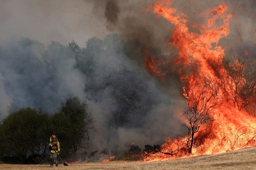 A firefighter changes position during operations to battle a wildfire in the village of Parafita, Galicia region, Spain, August 12, 2025. REUTERS/Violeta Santos Moura