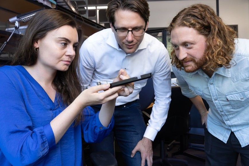 Erin Kunz, Frank Willett y Benyamin Meschede-Krasa inspeccionan un microelectrodo array.