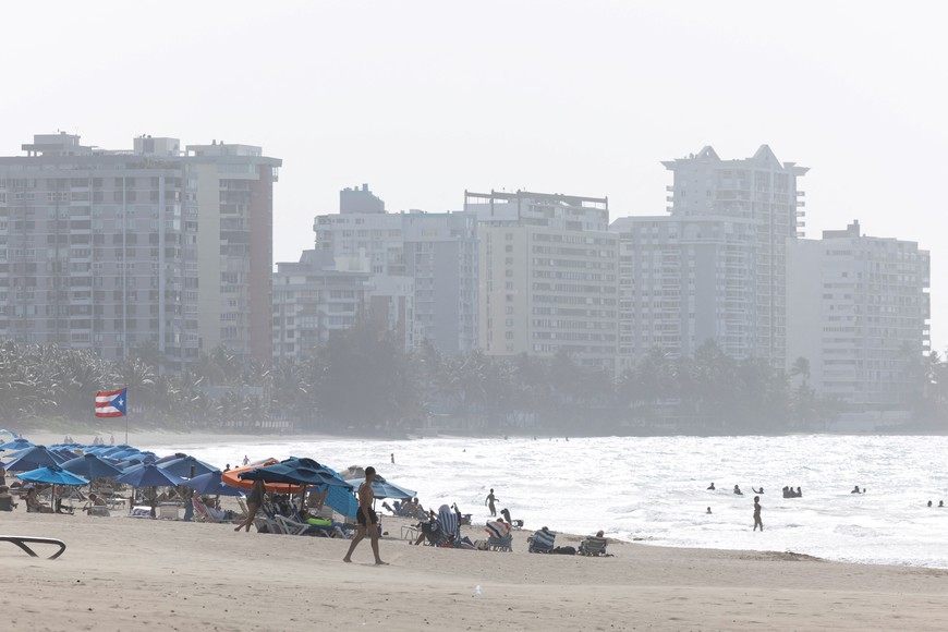 People enjoy the beach as a cloud of dust from the Sahara Desert blankets the Caribbean Sea, in Carolina, Puerto Rico, June 2, 2025. REUTERS/Ricardo Arduengo