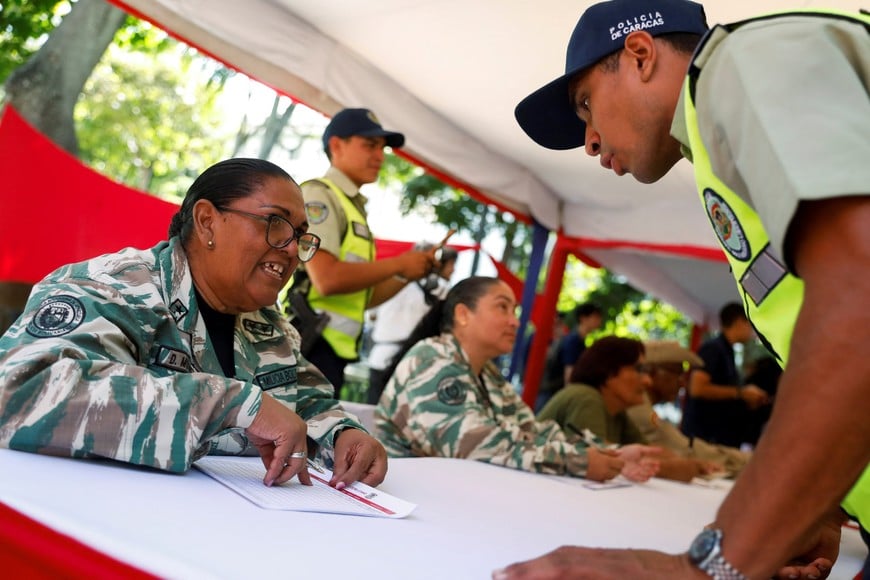A woman from the Bolivarian National Militia registers a police officer to enlist in the militia following President Nicolas Maduro's call for a nationwide recruitment drive, amid rising tensions with the United States over the deployment of U.S. warships in the region, in Caracas, Venezuela, August 23, 2025. REUTERS/Leonardo Fernandez Viloria