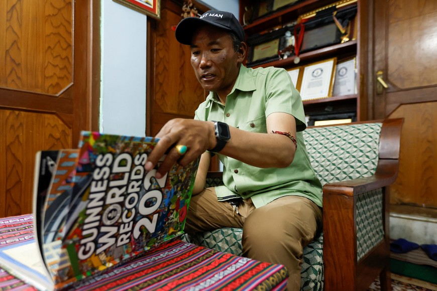 Kami Rita Sherpa, 53, a Nepali Mountaineer who climbed Mount Everest for a record 28 times, goes through the Guinness World Records 2021 book to show his pictures on them after an interview with Reuters at his rented apartment in Kathmandu, Nepal May 28, 2023. REUTERS/Navesh Chitrakar
