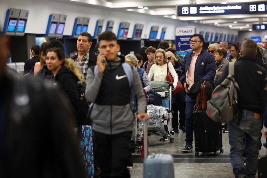 A man holds his luggage as he waits in line at the Aeroparque International Jorge Newbery airport as Argentine air traffic controllers strike for improved working conditions and higher wages, in Buenos Aires, Argentina, August 26, 2025. REUTERS/Agustin Marcaria
