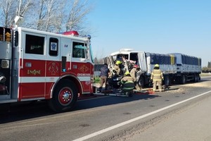 Personal de bomberos rescatando al chofer de la cabina.