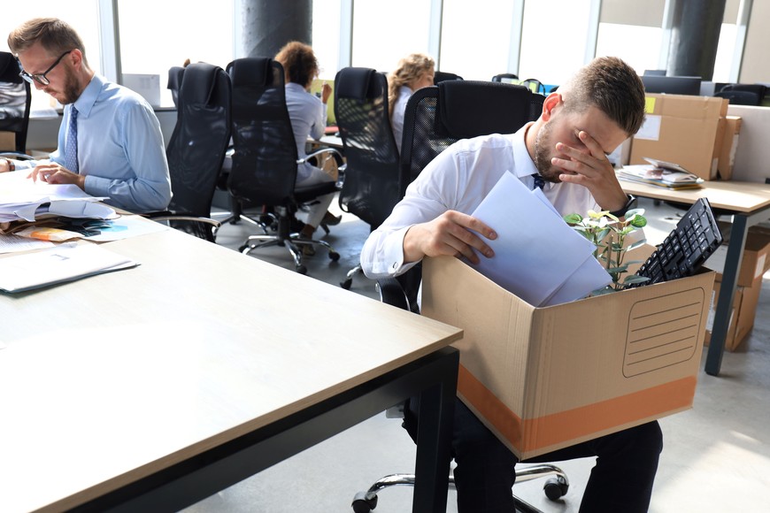 Sad dismissed worker are taking his office supplies with him from office.