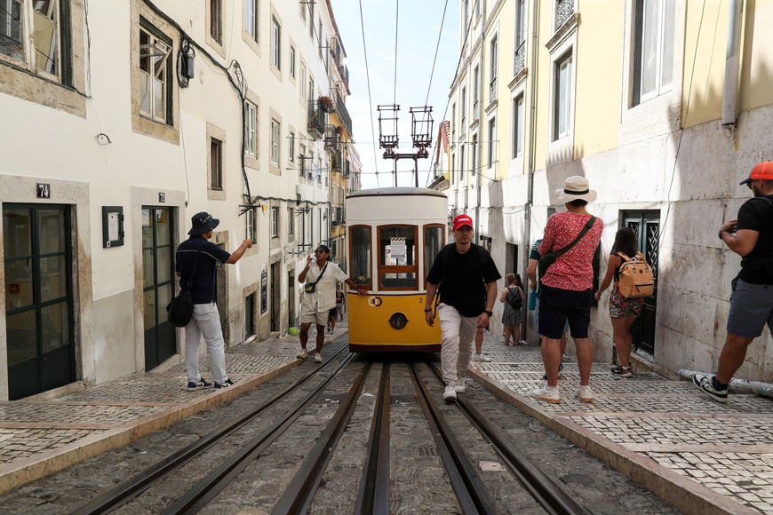People walk next to a railway car of the Bica Funicular after Lisbon's funiculars were suspended in the aftermath of the Gloria funicular railway car derailment and crash, a popular tourist attraction, which resulted in multiple casualties, according to authorities, in Lisbon, Portugal, September 4, 2025. REUTERS/Pedro Rocha