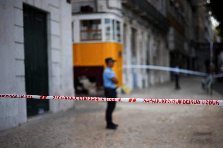 A police officer stands guard behind a tape blocking the site of the derailment and crash of the Gloria funicular railway car, a popular tourist attraction, which resulted in multiple casualties, in Lisbon, Portugal, September 4, 2025. REUTERS/Pedro Nunes