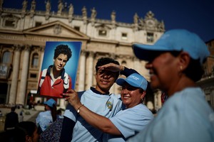 A woman holds a picture of Carlo Acutis on the day Pope Leo XIV leads a Holy Mass for the canonisation of Carlo Acutis, a British-born Italian boy who will become the first millennial to be made a Catholic saint, and Pier Giorgio Frassati, in St. Peter's Square at the Vatican, September 7, 2025. REUTERS/Guglielmo Mangiapane