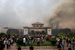 Demonstrators gather as smoke rises from the Parliament complex following fire set during a protest against Monday's killing of 19 people after anti-corruption protests that were triggered by a social media ban, which was later lifted, during a curfew in Kathmandu, Nepal, September 9, 2025. REUTERS/Adnan Abidi            TPX IMAGES OF THE DAY