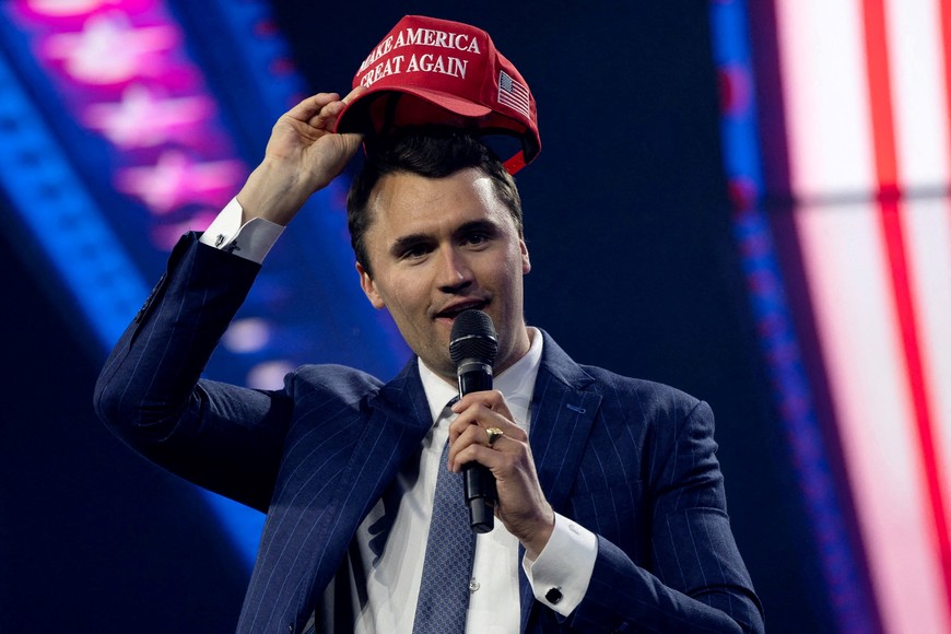 FILE PHOTO: Charlie Kirk, Turning Point USA founder, puts on a MAGA hat during the AmericaFest 2024 conference sponsored by conservative group Turning Point in Phoenix, Arizona, U.S. December 19, 2024.  REUTERS/Cheney Orr/File Photo
