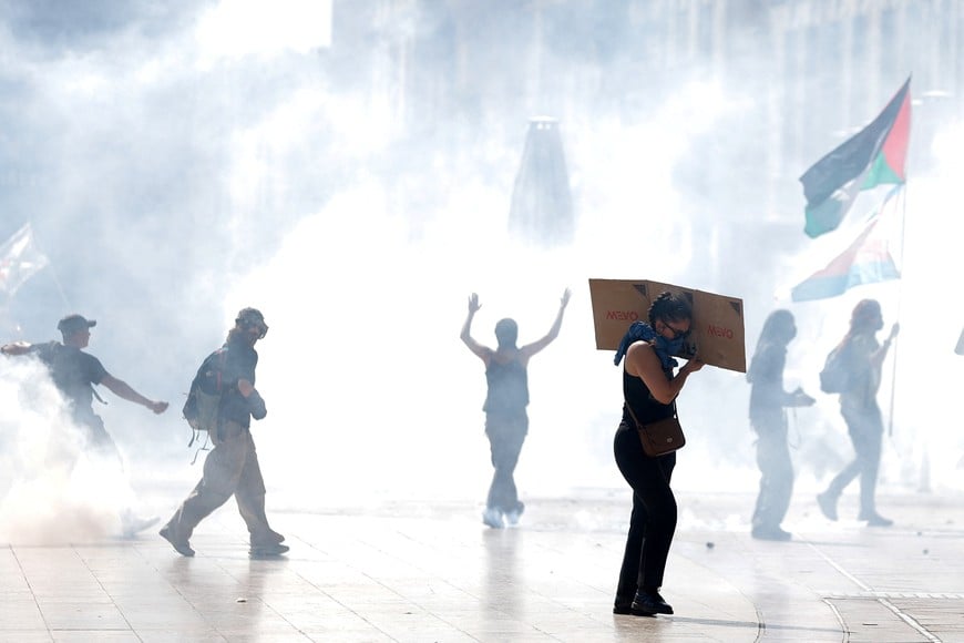 A protester shields herself with a sign as tear gas spreads amid clashes with police during a demonstration, as part of a grassroots protest movement called "Bloquons Tout" ("Let's Block Everything") calling for nationwide all-day disruption, in Montpellier, France, September 10, 2025. REUTERS/Manon Cruz