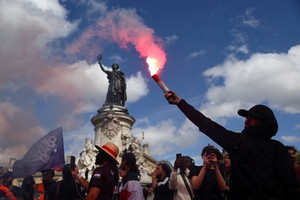 A masked protester holds a red flare during a demonstration at the Place de la Republique during a day of protests in Paris as part of a grassroots protest movement called "Bloquons Tout" ("Let's Block Everything") calling for nationwide all-day disruptions, France, September 10, 2025. REUTERS/Abdul Saboor