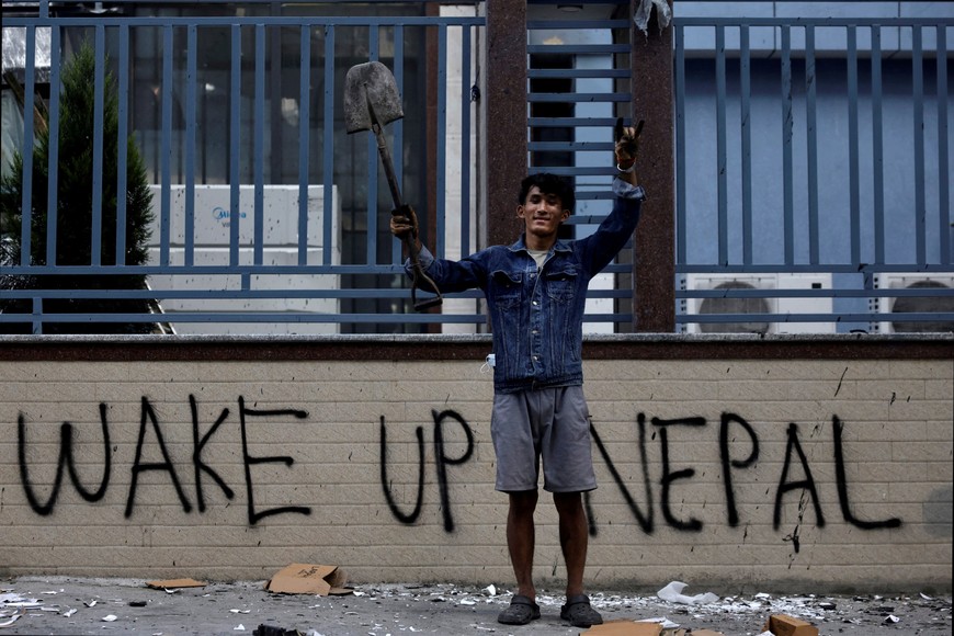 Sabin Tamang, 20, who works in a restaurant and participated in a Gen-Z protest, holds up a shovel while posing for a photograph next to graffiti as he takes part in a cleaning campaign following Monday's deadly anti-corruption protests in Kathmandu, Nepal, September 10, 2025. "To develop our country, we need to choose good people instead of choosing relatives"'  said Sabin Tamang. We should hand over the future of the country to a person who has good ideology and is not self-centred." REUTERS/Navesh Chitrakar TPX IMAGES OF THE DAY