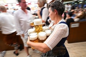 A waitress holds mugs of beer to serve during the official opening day of the 190th Oktoberfest, the world's largest beer festival in Munich, Germany, September 20, 2025. REUTERS/Angelika Warmuth