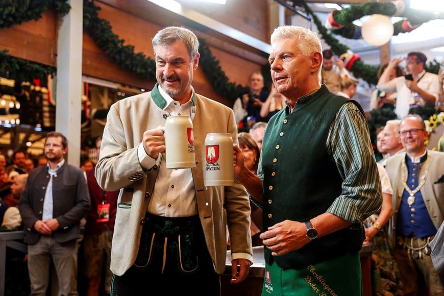 Bavarian Minister-President Markus Soeder and Mayor of Munich Dieter Reiter pose with beers as they visit the Schottenhamel tent, on the day of the official opening of the 190th Oktoberfest, the world's largest beer festival in Munich, Germany, September 20, 2025. REUTERS/Maryam Majd
