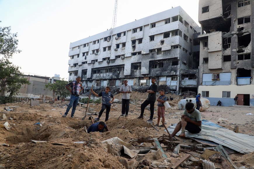 Palestinians gather as they bury loved ones, who were killed in Israeli fire, according to medics, in the yard of Al-Shifa hospital, as they are unable to move them to a cemetery due to the Israeli ground offensive, in Gaza City, September 23, 2025. REUTERS/Ebrahim Hajjaj