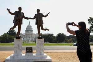 A woman takes a photo of a pop-up statue depicting U.S. President Donald Trump and disgraced financier and sex offender Jeffrey Epstein dancing together near the U.S. Capitol in Washington, D.C., U.S., September 23, 2025. REUTERS/Kevin Lamarque