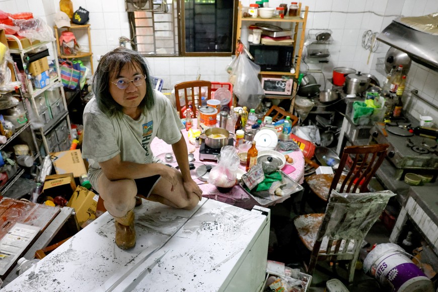 A resident sits on top of a refrigerator in a mud-covered kitchen after flooding brought by Super Typhoon Ragasa in Hualien, Taiwan, September 25, 2025. REUTERS/Ann Wang