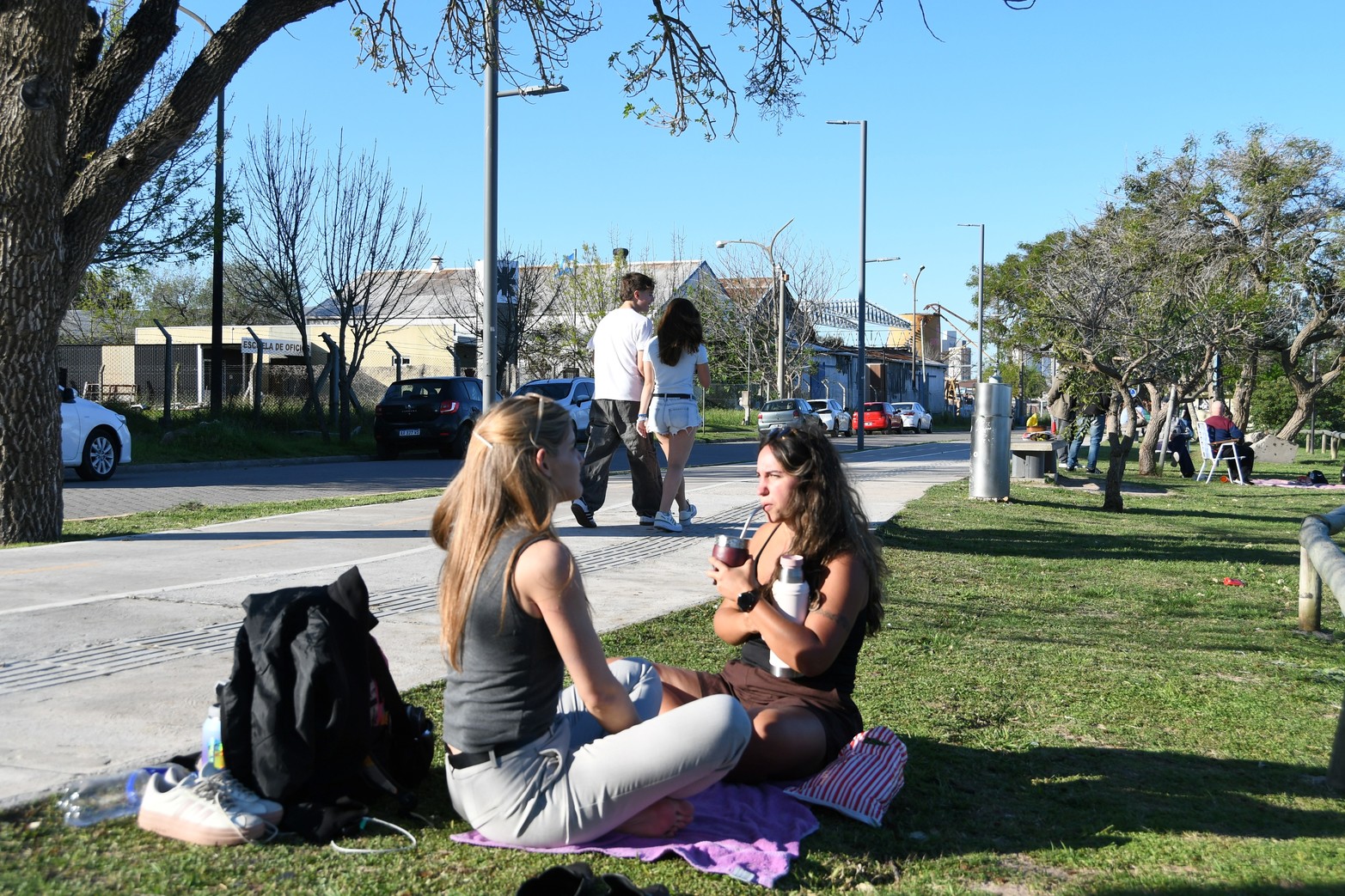 Dos amigas toman mate sentadas sobre el césped del Paseo Costero.