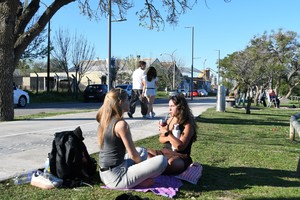 Dos amigas toman mate sentadas sobre el césped del Paseo Costero.