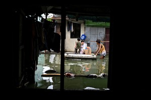 Children use a makeshift raft to cross a flooded street following rains, intensified by severe Tropical Storm Bualoi, in Dela Paz, Binan, Laguna province, Philippines, September 26, 2025.  REUTERS/Noel Celis
