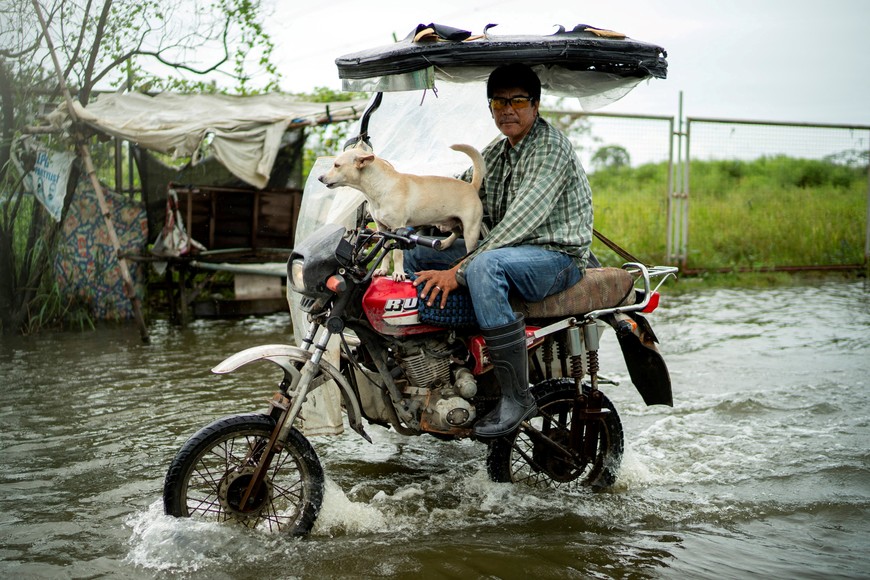 A motorist with a dog wades through a flooded road, following heavy rains intensified by Super Typhoon Ragasa, in Apalit, Pampanga province, Philippines, September 23, 2025. REUTERS/Lisa Marie David      TPX IMAGES OF THE DAY