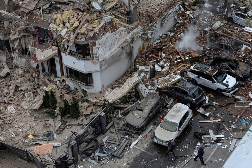 People walk next to a damaged building and vehicles in a residential neighbourhood hit during a Russian drone and missile strike, amid Russia's attack on Ukraine, on the outskirts of Kyiv, Ukraine, September 28, 2025. REUTERS/Anatolii Stepanov