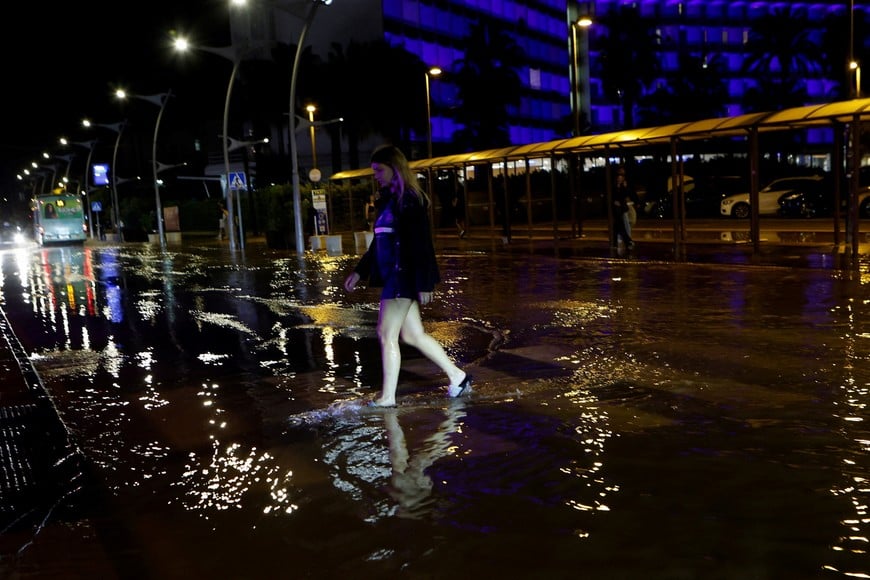 A tourist crosses a flooded street after storm Gabrielle hit the island in Ibiza, Spain September 30, 2025. REUTERS/Francisco Ubilla