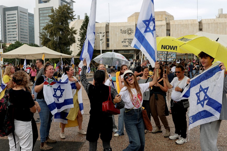 People celebrate holding Israeli flags after U.S. President Donald Trump announced that Israel and Hamas agreed on the first phase of a Gaza ceasefire, at the "Hostages square", in Tel Aviv, Israel, October 9, 2025. REUTERS/Ronen Zvulun