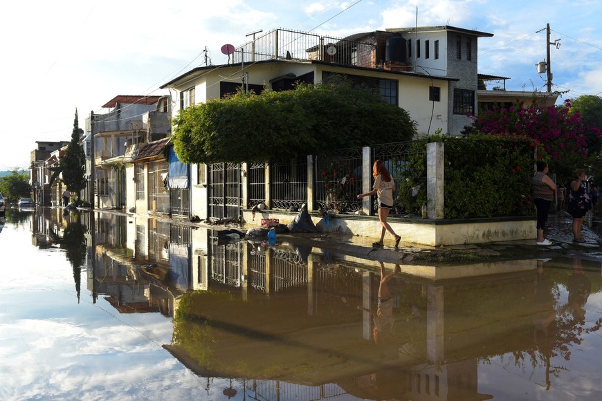 A woman walks near a flooded street after torrential rains that that caused an overflow of rivers, causing flooding in Poza Rica, Veracruz state, Mexico October 10, 2025. REUTERS/Rolando Ramos