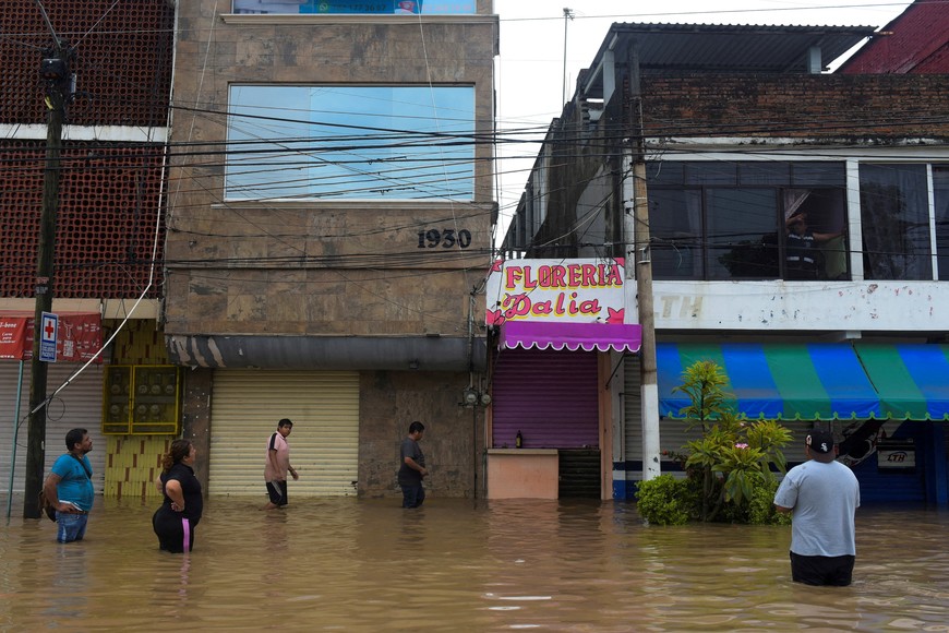 People wade through a flooded street after torrential rains that caused an overflow of rivers in Poza Rica, Veracruz state, Mexico, October 10, 2025. REUTERS/Rolando Ramos     TPX IMAGES OF THE DAY