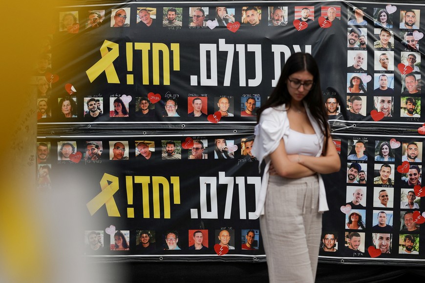 A woman walks past banners with images of hostages kidnapped during the deadly October 7, 2023 attack, after a ceasefire between Israel and Hamas in Gaza went into effect, at "Hostages square", in Tel Aviv, Israel, October 12, 2025. REUTERS/Stoyan Nenov