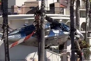 Restos del helicóptero siniestrado entre palmeras y autos en Huntington Beach. Foto: Gentileza