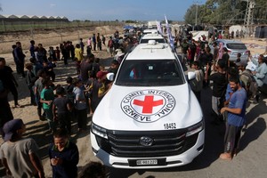 Palestinians gather around Red Cross vehicles transporting hostages, held in Gaza since the deadly October 7, 2023 attack, following their handover as part of a ceasefire and hostages-prisoners swap deal between Hamas and Israel, in the central Gaza Strip, October 13, 2025. REUTERS/Stringer      TPX IMAGES OF THE DAY