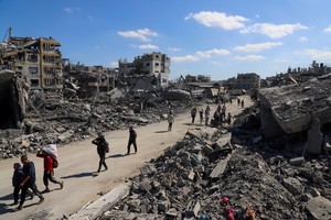 Palestinians walk past the rubble of destroyed buildings, amid a ceasefire between Israel and Hamas, in Gaza City, October 14, 2025. REUTERS/Ebrahim Hajjaj