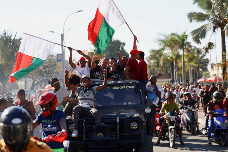 A pickup truck drives with occupants waving flags after military joined protesters gathered outside the town hall on Independence Avenue during a nationwide youth-led demonstration against frequent power outages and water shortages, in Antananarivo, Madagascar, October 14, 2025. REUTERS/Siphiwe Sibeko