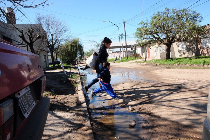 Una madre y su hija, saltando efluentes cloacales en plena calle. Crédito: Archivo Flavio Raina