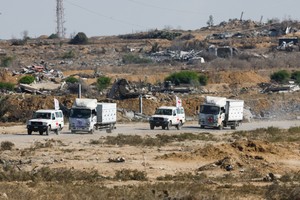 Red Cross vehicles escort trucks transporting the bodies of deceased Palestinians held by Israel during the war, after their release, amid a ceasefire between Israel and Hamas, in Khan Younis, southern Gaza Strip, October 15, 2025. REUTERS/Mahmoud Issa