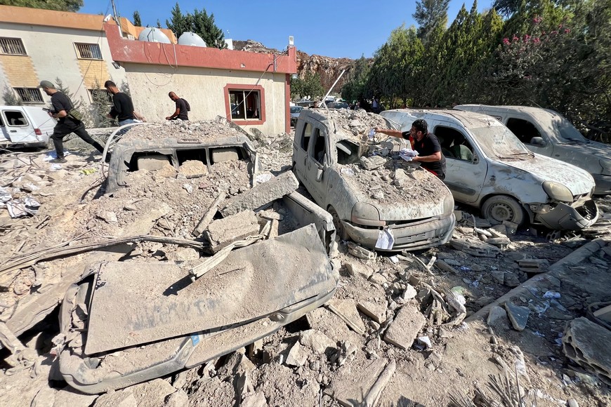 (251017) -- ANSAR, 17 octubre, 2025 (Xinhua) -- Personas revisan vehículos destruidos tras ataques aéreos israelíes, en Ansar, Líbano, el 17 de octubre de 2025. Una persona murió y otras siete resultaron heridas el jueves en una serie de ataques aéreos israelíes contra posiciones de Hizbulá en el sur de Líbano, dijo el Centro de Operaciones de Emergencia del Ministerio de Salud. (Xinhua/Ali Hashisho) (oa) (ra) (ce)