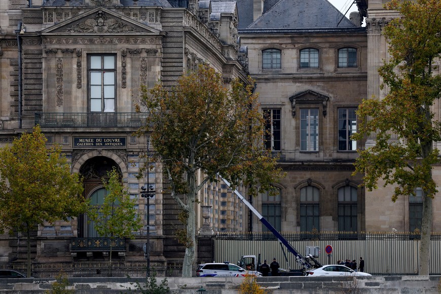Police officers work next to a crane and a window believed to have been used in what the French Interior Ministry said was a robbery at the Louvre museum during which jewellery was stolen, in Paris, France, October 19, 2025. REUTERS/Gonzalo Fuentes