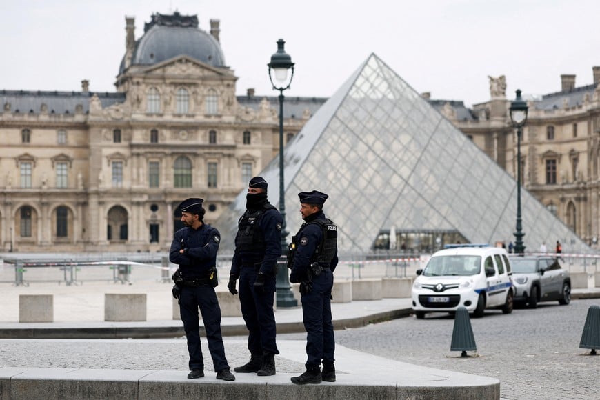 Police officers stand near the pyramid of the Louvre museum after reports of a robbery, in Paris, France, October 19, 2025. REUTERS/Gonzalo Fuentes     TPX IMAGES OF THE DAY
