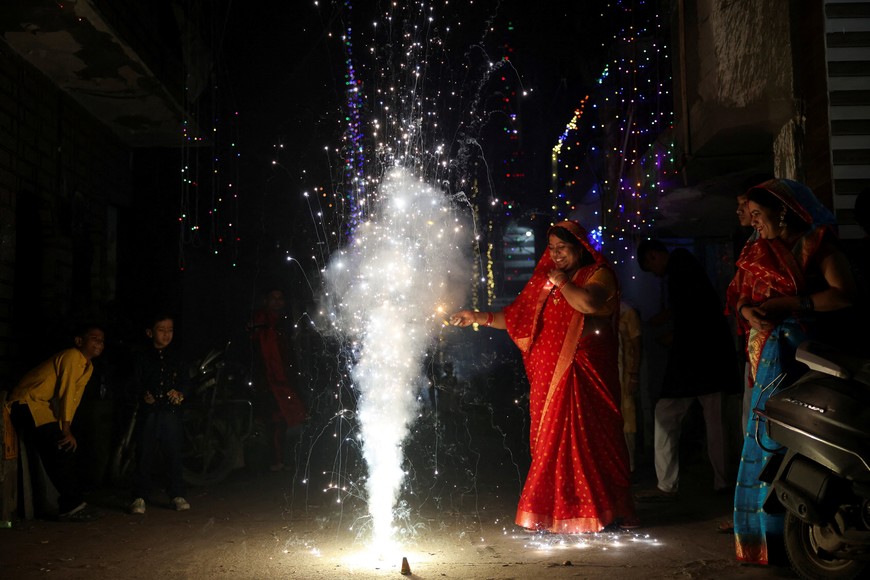 A woman lights fireworks to celebrate Diwali, the Hindu festival of lights, in New Delhi, India, October 20, 2025. REUTERS/Bhawika Chhabra