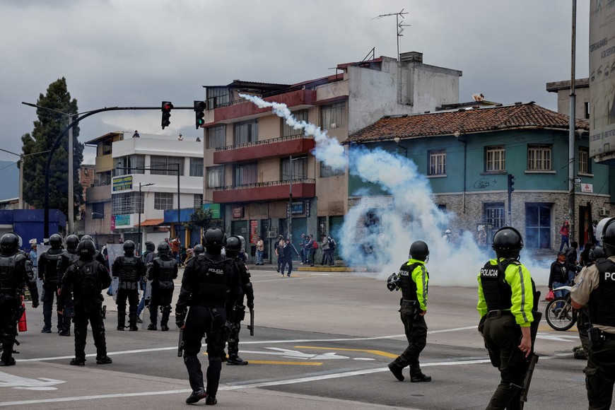 People stand near a tear gas smoke and police officers as indigenous organisations and other social movements called out for a peaceful march of resistance, in Quito, Ecuador, October 12, 2025. REUTERS/Karen Toro     TPX IMAGES OF THE DAY